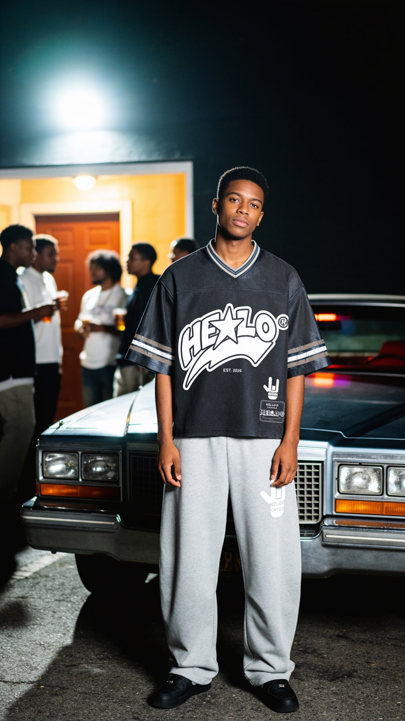 Footprint Apparel men's streetwear — young man in a black HE★LO jersey by a vintage car at night