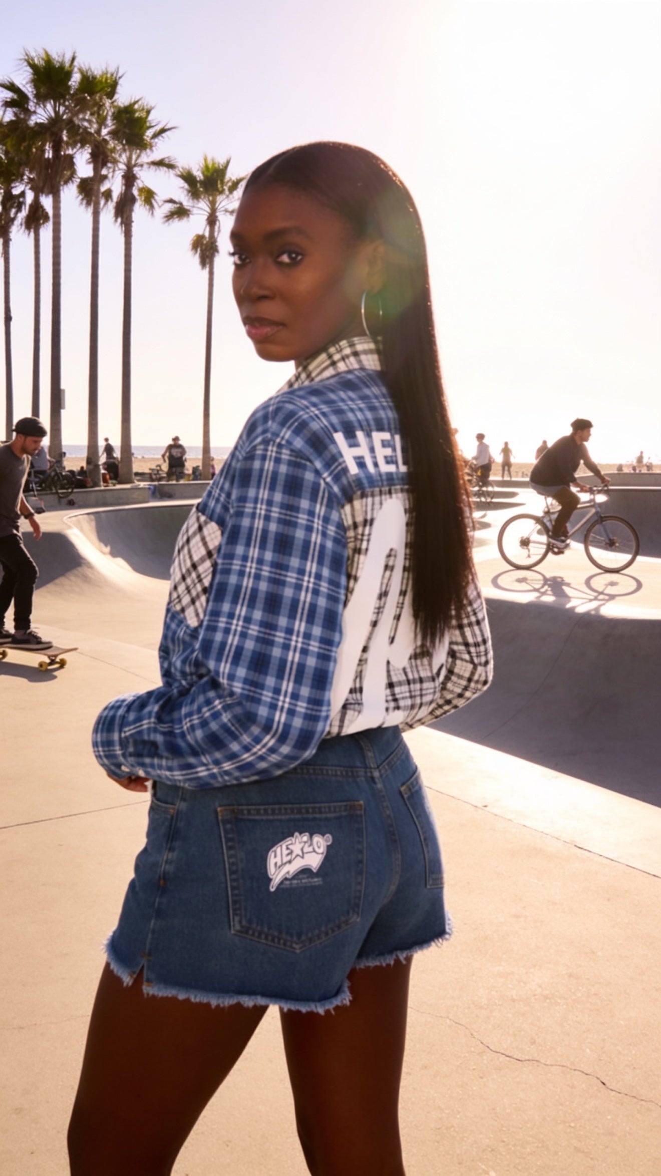 Footprint Apparel — woman with her back to the camera wearing the blue plaid shirt and denim shorts at a skatepark
